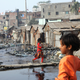 A girl walks across polluted water in a slum in Dhaka, Bangladesh